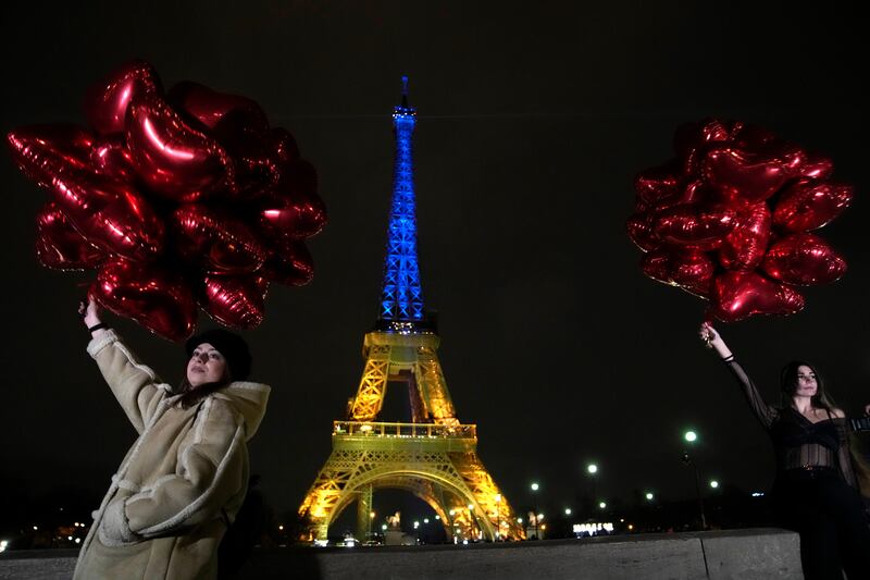Tourists in Paris with balloons as the Eiffel Tower is lit in Ukraine's colours. AP