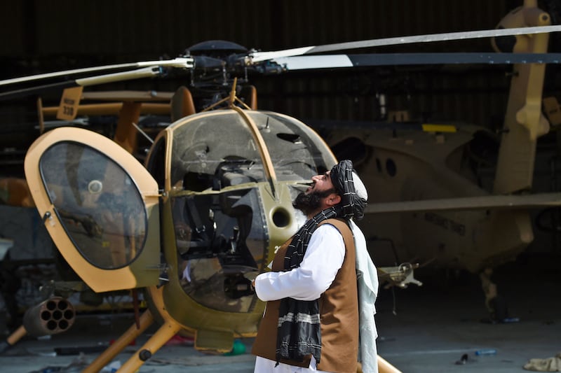 A Taliban member stands next to a damaged helicopter. AFP