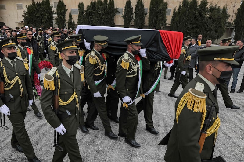 An honour guard carries Mr Qurei's coffin, draped in the Palestinian flag. AFP