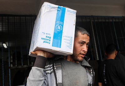 A Palestinian man carries a box of aid distributed in Deir Al Balah before Eid Al Fitr. Reuters
