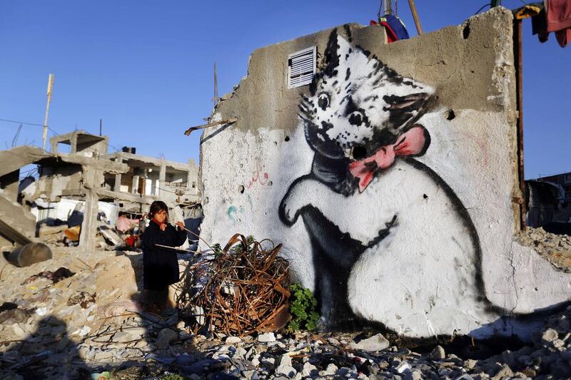 A Palestinian child stands next to a mural of a kitten, said to have been painted by British street artist Banksy, on the remains of a house that was destroyed during the 50-day war between Israel and Hamas militants in the summer of 2014, in the Gaza Strip town of Beit Hanun. Mohammed Abed / AFP Photo 

