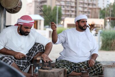 Rashid Al Antari, right, at the blacksmith station at the Al Hosn Festival. Khushnum Bhandari / The National 
