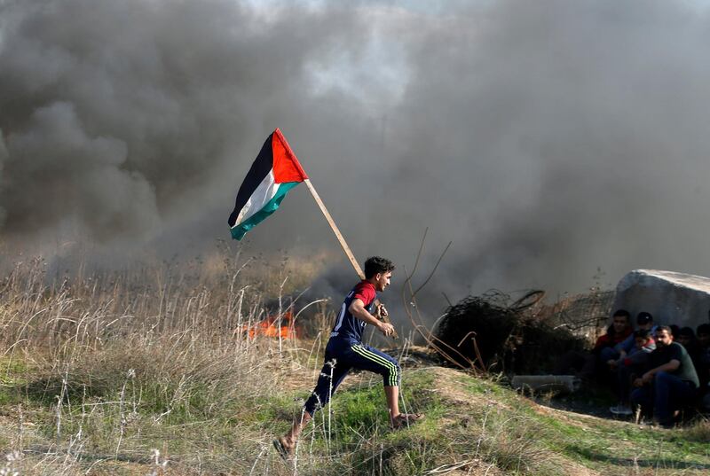 A protester holds a Palestinian flag as he runs during clashes with Israeli troops as Palestinians call for a 'day of rage' in response to U.S. President Donald Trump's recognition of Jerusalem as Israel's capital, near the border with Israel in the east of Gaza City December 8, 2017. REUTERS/Mohammed Salem