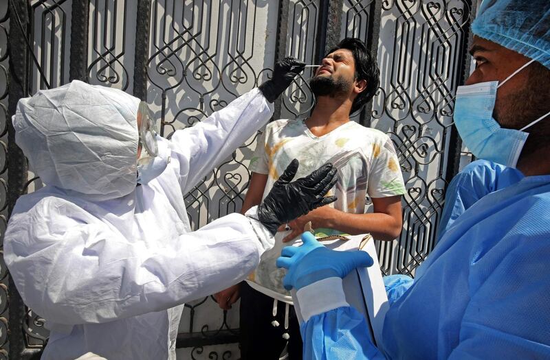 TOPSHOT - Iraqi public hospital specialised doctors test a resident for COVID-19 in the capital Baghdad's suburb of Sadr City on April 2, 2020, as part of actions taken by the authorities against the spread of the novel coronavirus. The process of examining citizens at their residences in Baghdad's eastern districts was launched in order to detect infection with the virus in the area where many cases were found to isolate patients and take them for treatment in public hospitals to limit the spread of the pandemic. / AFP / AHMAD AL-RUBAYE
