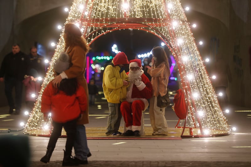 People chat with a person dressed as Santa Claus in the centre of Tbilisi, Georgia. EPA