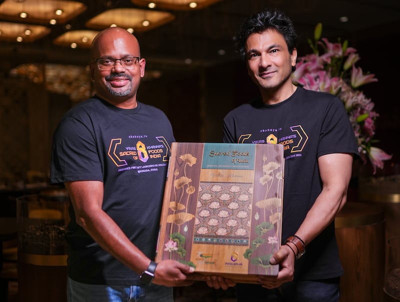 Chef Vikas Khanna, right, with Ganesh Raju, the chief executive of Akshaya.io, and a copy of Khanna's limited edition book 'Sacred Foods of India'. Photo: Vikas Khanna