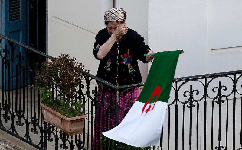 A woman wipes her face while carrying a national flag in Algeria. AP Photo