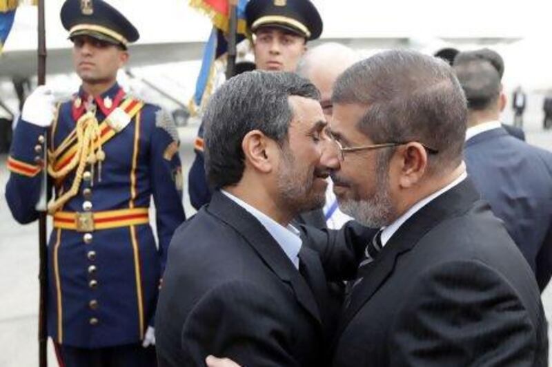 Egyptian President Mohammed Morsi (right) greets President Ahmadinejad at the Cairo airport.