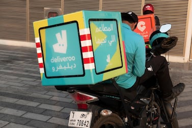 Riders from food delivery services Deliveroo and Carriage check phones for their next assignment. Alamy.