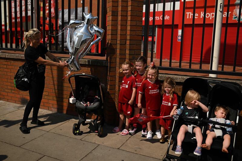 Liverpool fans pose with a trophy-shaped balloon outside Anfield stadium. AFP