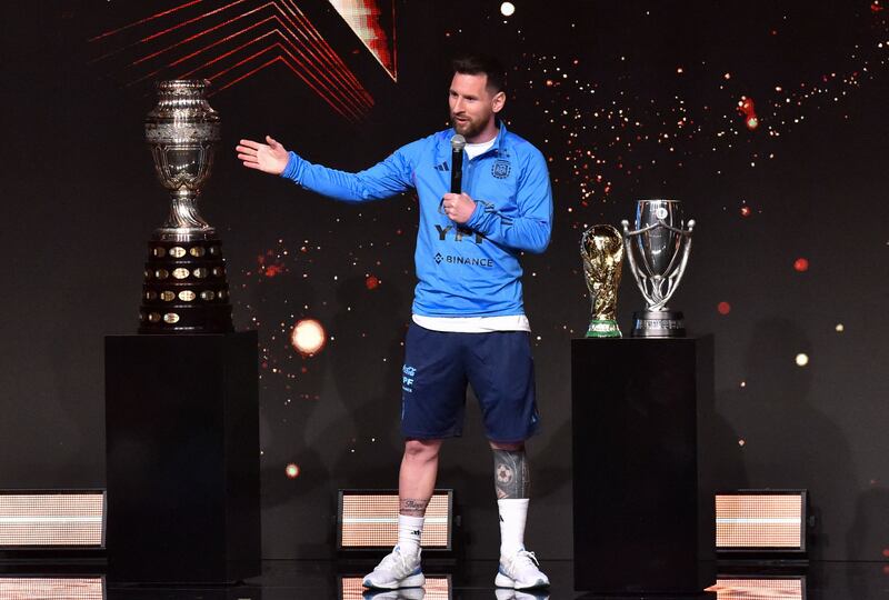 Argentina's Lionel Messi alongside the Copa America trophy, left, and replicas of the World Cup and Finalissima trophies. AFP