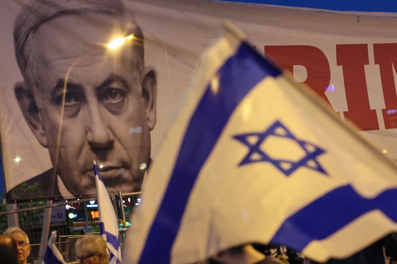 Demonstrators raise Israeli flags near a banner depicting Israeli Prime Minister Benjamin Netanyahu. AFP