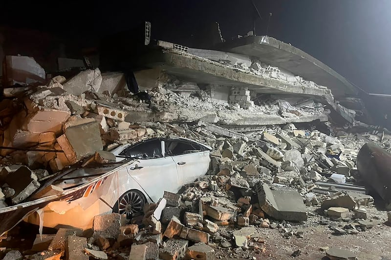 A car is buried underneath the rubble of a collapsed building in Azmarin, a town in Syria's Idlib province. AP