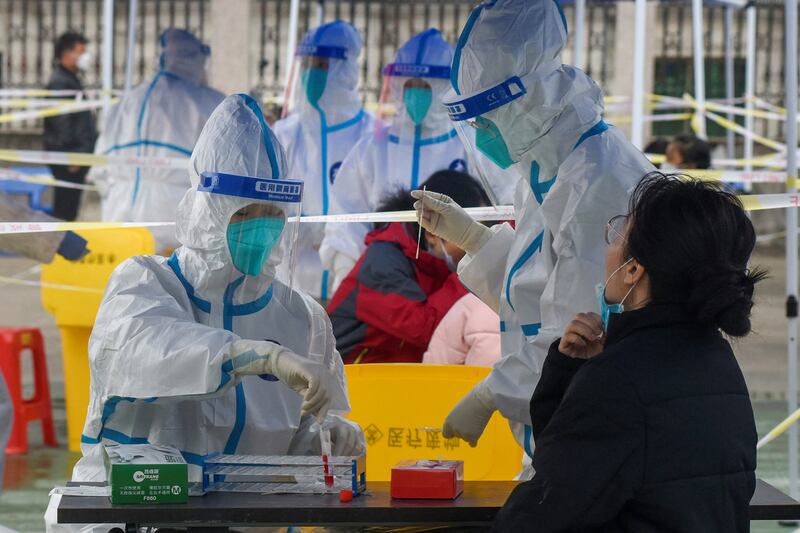 Medical workers in protective suits collect swabs from residents at a Covid-19 testing site in Ningbo, China. Reuters