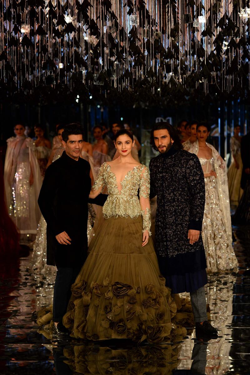 Designer Manish Malhotra with his showstoppers: Bollywood's Alia Bhatt, who wore a bejeweled jacket top and nude lehenga with a long trail and rose embellishments, and Ranveer Singh, in an embroidered navy blue, velvet sherwani with a pair of micro-check trousers. AFP