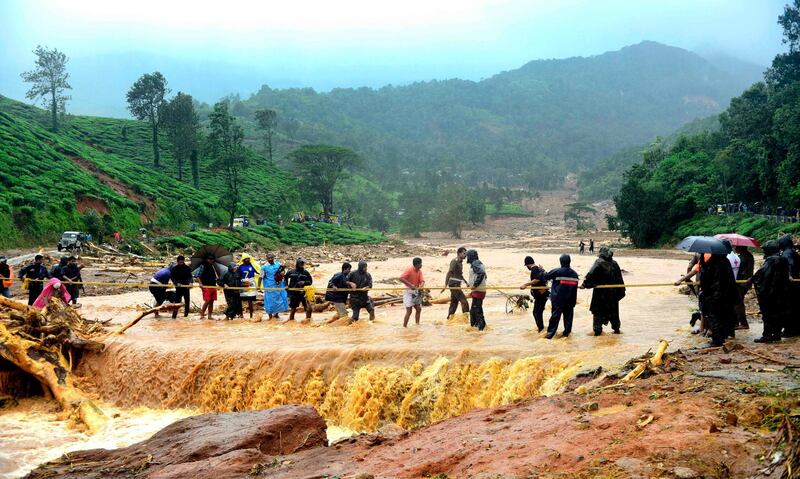 People walk through flood waters after a landslide in Meppadi, Wayanad district, in the Indian state of Kerala on August 9, 2019. Floods that have killed more than 20 people forced the closure of Kochi international airport on August 9 as the south Indian state of Kerala confronted a second straight year of crisis level downpours. / AFP / STR
