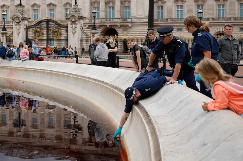 A police officer takes a sample of water from the fountain at the Queen Victoria Memorial outside Buckingham Palace. AFP