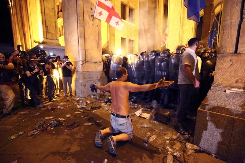 An opposition demonstrator stands in front police line at Georgian Parliament to call for the resignation of the speaker of the Georgian Parliament in Tbilisi, Georgia, Friday, June 21, 2019. Police have fired a volley of tear gas at a massive throng of protesters outside the Georgian national parliament, who are trying to storm the building and are demanding the government's resignation.(AP Photo/Zurab Tsertsvadze)