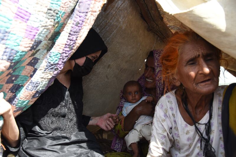 Jolie with a young mother in a makeshift shelter in Dadu, Pakistan. Photo: International Rescue Committee