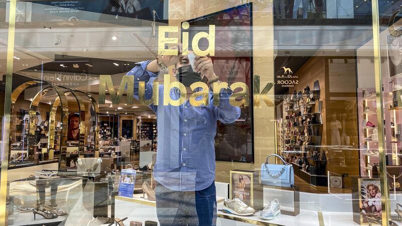 A shop attendent puts up an Eid Mubarak sticker on a shop window in the mall. Eid decorations in Festival City Mall with shoppers preparing for Eid on May 10th, 2021. 
Antonie Robertson / The National.
Reporter: Patrick Ryan for National.