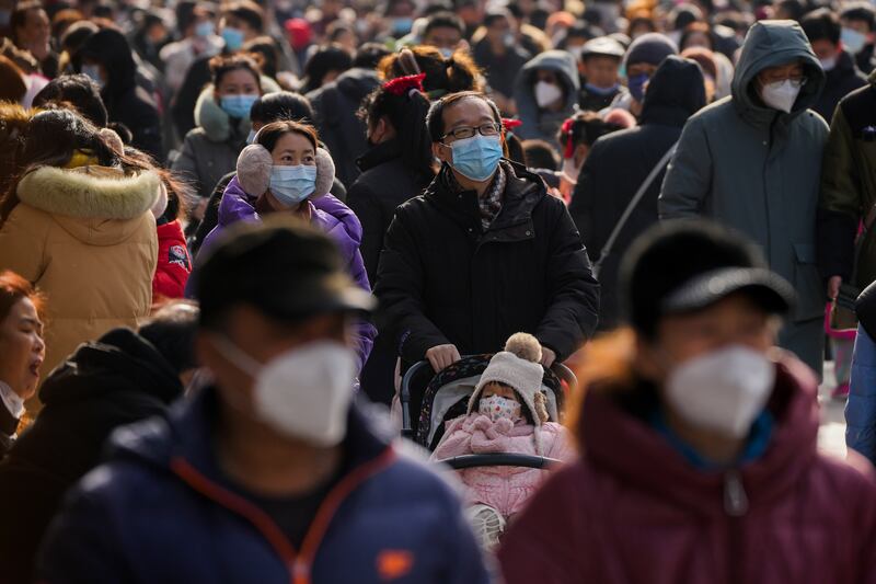 Pedestrians with face masks at Qianmen shopping street in central Beijing. China has reopened its borders after three years. AP