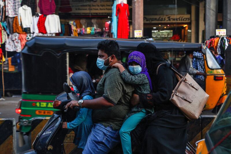 An Indian family wearing face masks as a precaution against the coronavirus rides on a scooter through a street in Hyderabad, India. India has more than 9 million cases of coronavirus, second behind the United States. AP