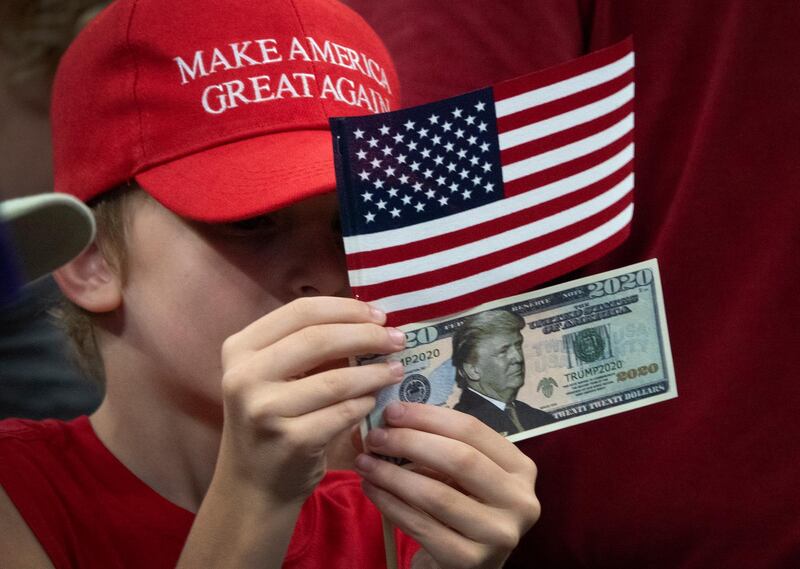 A child holds a '2020' US dollar bill with a picture of US President Donald Trump during Trump's 2020 re-election bid announcement in Orlando, Florida, USA.  EPA