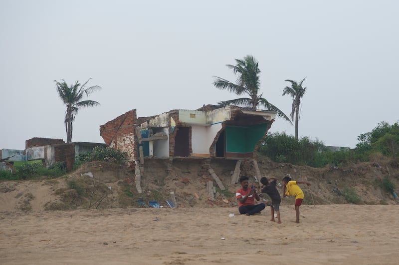 Former inhabitants of the of Podemepta village sit at an abandoned house. The houses once belonged to a prosperous fishermen community but are now a testimony of widespread devastation caused by climate change.