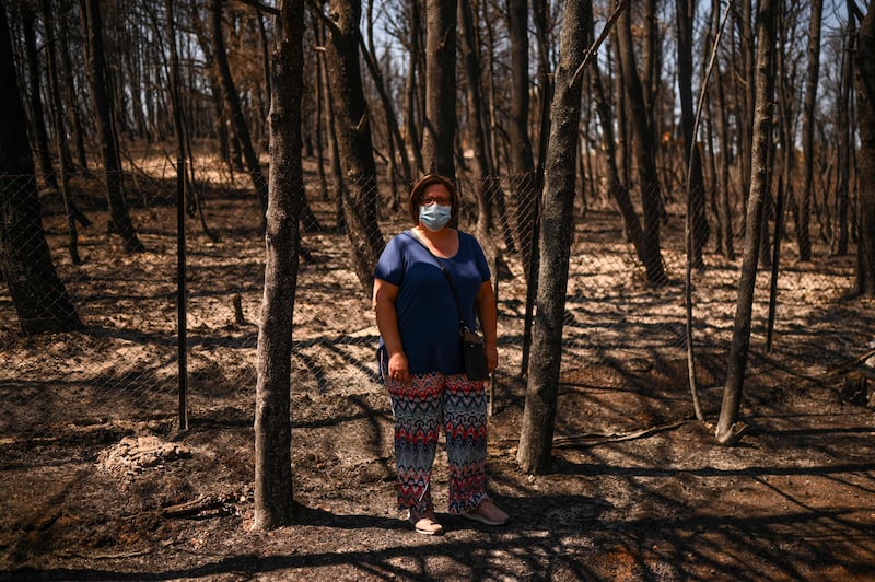 Eleni Haniosakis stands next to her burnt home in the village of Krioneri, north of Athens.