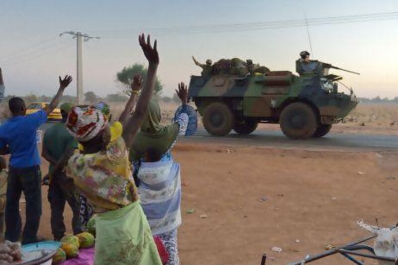Malian people wave to French soldiers as a convoy of armoured vehicles leave Bamako for a ground deployment to the north of Mali.