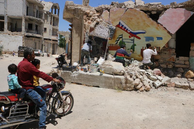 Graphic artist Aziz Al-Asmar drawing on ruined walls in Bennesh.