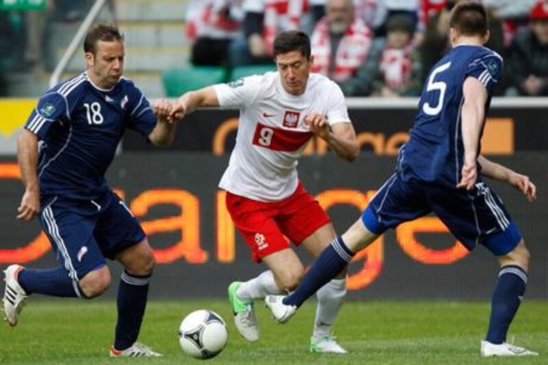 Robert Lewandowski (C) of Poland fights for the ball against Andorra's Manel Josep Ayala (L) and Emili Garcia during their international friendly soccer match in Warsaw June 2, 2012. REUTERS/Peter Andrews (POLAND - Tags: SPORT SOCCER)