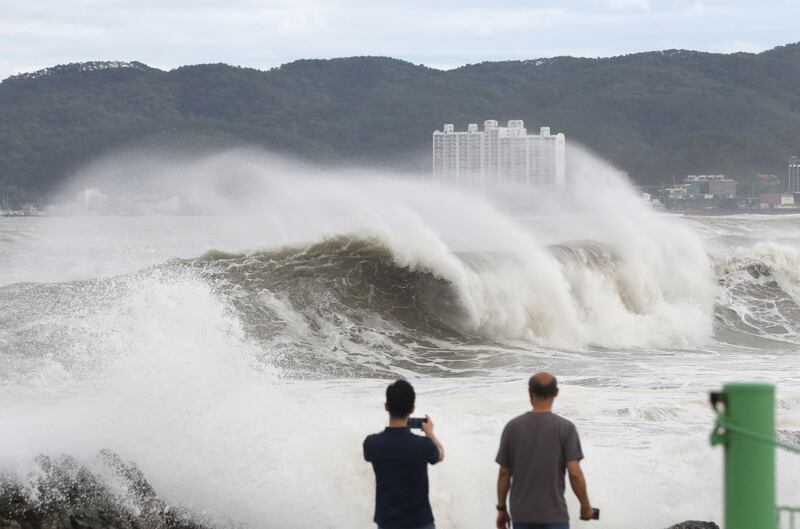 People watch the waves brought by Typhoon Hinnamnor in Ulsan on September 6, 2022, as the typhoon hit South Korea's southern provinces.  (Photo by YONHAP  /  AFP)  /  - South Korea OUT  /  REPUBLIC OF KOREA OUT  NO ARCHIVES  RESTRICTED TO SUBSCRIPTION USE
