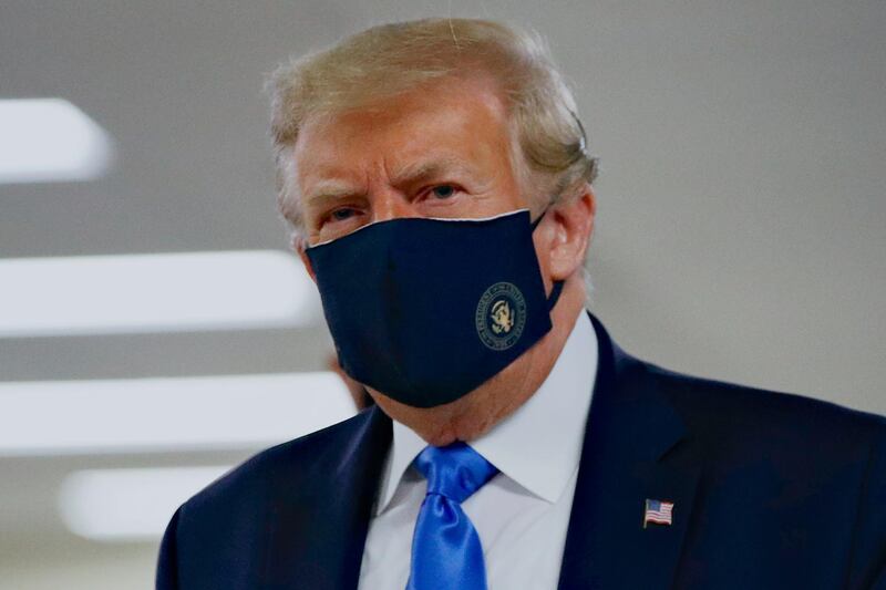 FILE - In this Saturday, July 11, 2020, file photo, President Donald Trump wears a face mask as he walks down a hallway during a visit to Walter Reed National Military Medical Center in Bethesda, Md. When Trump wore a mask publicly for the first time on Saturday,  he chose a navy-blue one that bore the presidential seal. It also matched the color of his suit. (AP Photo/Patrick Semansky, File)