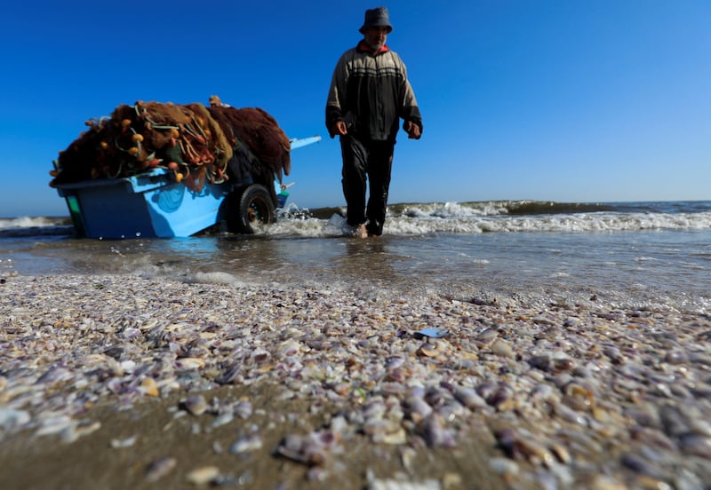 An Egyptian fisherman walks next to sand and seashells in front of his boat during low tide of water along a beach in the Red Sea shore at Port Said city, northeast of Cairo, Egypt May 27, 2022.  REUTERS / Amr Abdallah Dalsh