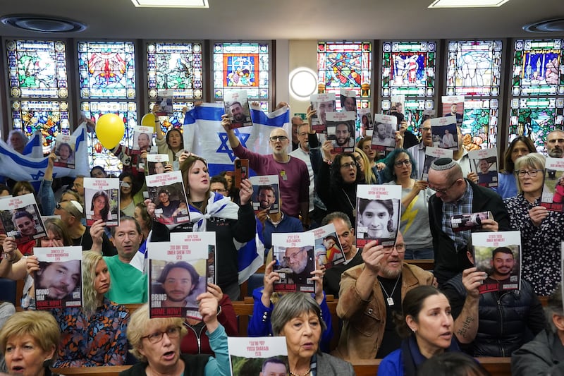 Family members of the hostages hold up images of those taken on October 7. PA
