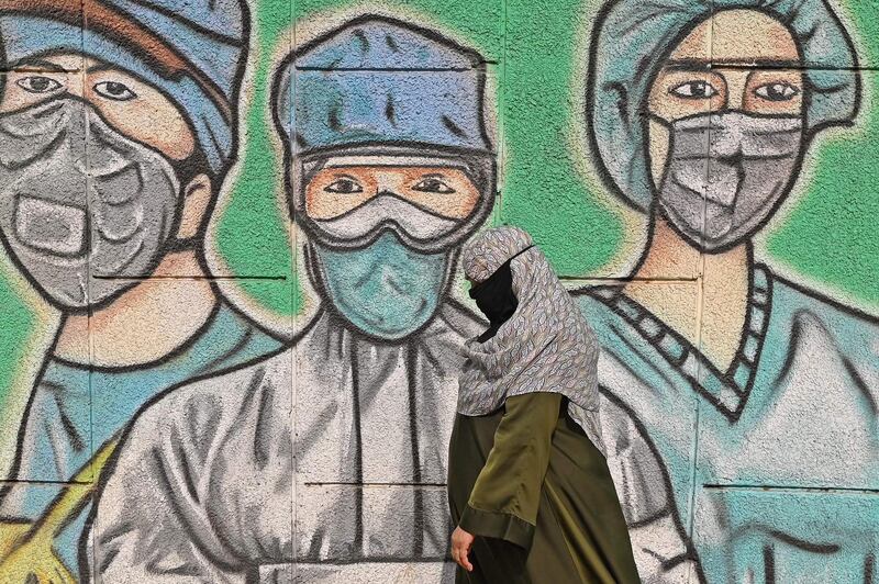 A person walks past a wall mural depicting frontline Covid-19 workers wearing face masks along a road in New Delhi, India, on March 21, 2021. AFP