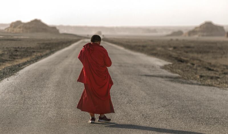 A Buddhist monk walks on the desert road.