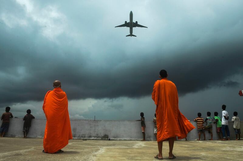Monks and children watch an international passenger flight take off from Kolkata, India after authorities eased coronavirus travel restrictions.  AFP