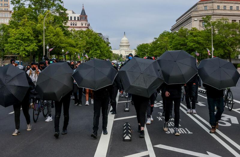 Demonstrators march with black umbrellas to conceal their faces while calling for racial justice and police reforms in Washington, US. Reuters