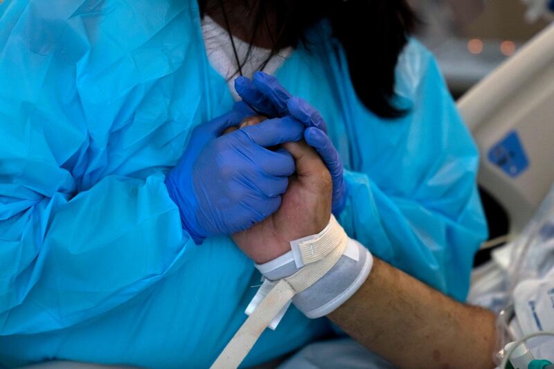 Patty Trejo, 54, holds the hand of her intubated husband, Joseph, in a Covid-19 unit at St. Jude Medical Center, in Fullerton, California. AP Photo