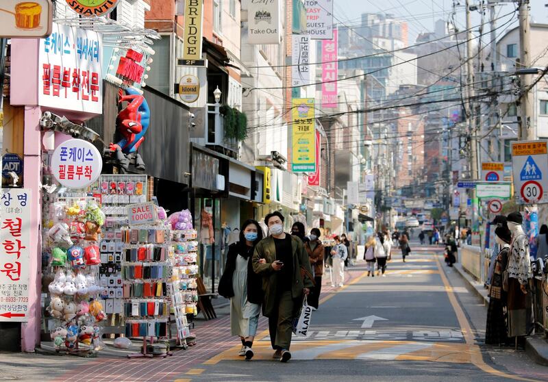 A couple wearing masks to protect against contracting the coronavirus disease (COVID-19) walk along a street in Seoul, South Korea, April 3, 2020.    REUTERS/Heo Ran