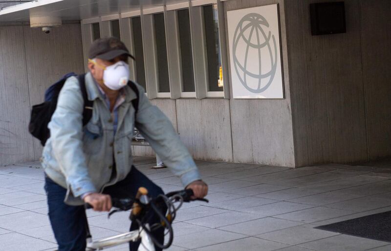 A man rides a bicycle past the headquarters of the World Bank Group as the International Monetary Fund (IMF) and World Bank hold their Spring Meetings virtually due to the outbreak of COVID-19, known as coronavirus, in Washington, DC, April 15, 2020.  / AFP / SAUL LOEB

