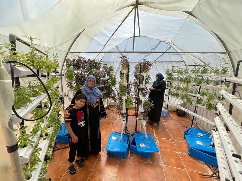 Hiyam Saeed, with her son, tends the rooftop plants. The rooftop plastic house is supported by German aid organisation Hilfe zur Selbsthilfe. Photos: Khaled Yacoub Oweis / The National