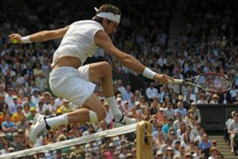 Argentina's Juan Martin Del Potro jumps over the net as he over-runs for a ball against Australia's Lleyton Hewitt on June 25, 2009.