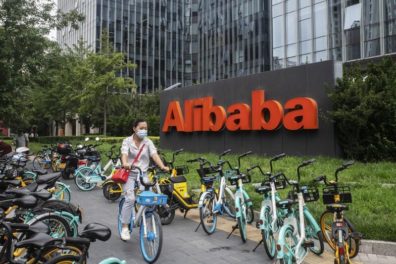 A cyclist wearing a protective mask rides past the Alibaba Group Holding Ltd. logo displayed in front of the company's building in Beijing, China, on Wednesday, Aug. 19, 2020. U.S. President Donald Trump is threatening to slap TikTok-style sanctions on more Chinese companies and Alibaba Group Holding Ltd., as the largest of them all, may be next in line. Photographer: Gilles Sabrie/Bloomberg