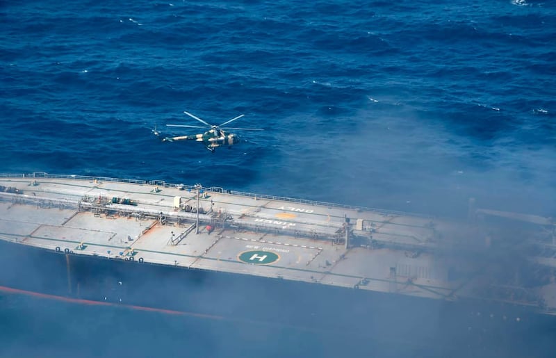 A chopper flies through smoke rising from the MT New Diamond, off the eastern coast of Sri Lanka in the Indian Ocean. Sri Lanka Air Force via AP