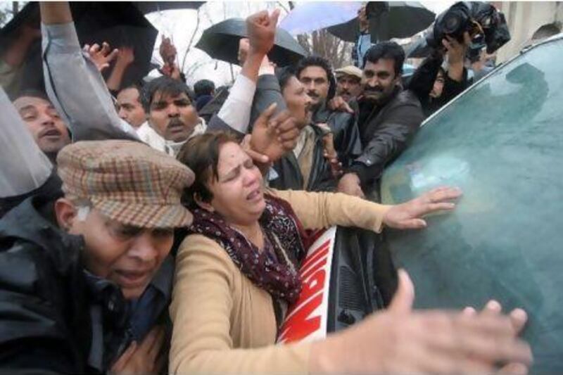 Supporters of Shahbaz Bhatti, the minister for minorities affairs, embrace an ambulance transporting his body, after he was killed by unknown armed men, in Islamabad.
