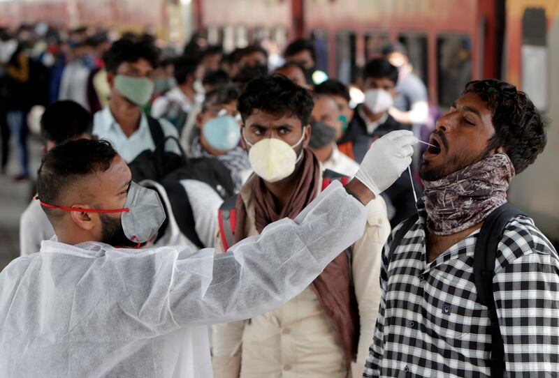 A health worker collects a swab sample from a traveller at a railway station to test for the coronavirus before allowing him to enter Mumbai, India. AP