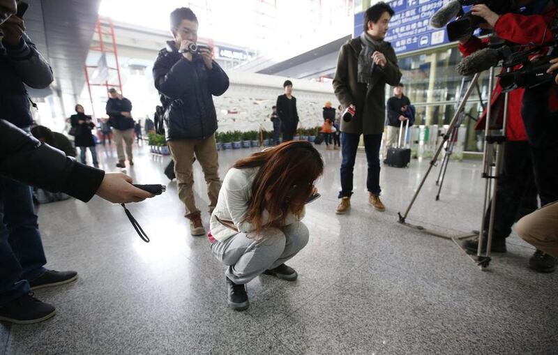 Journalists attempt to interview a woman who is the relative of a passenger on Malaysia Airlines flight MH370, as she crouches on the floor crying, at the Beijing Capital International Airport in Beijing. Reuters 